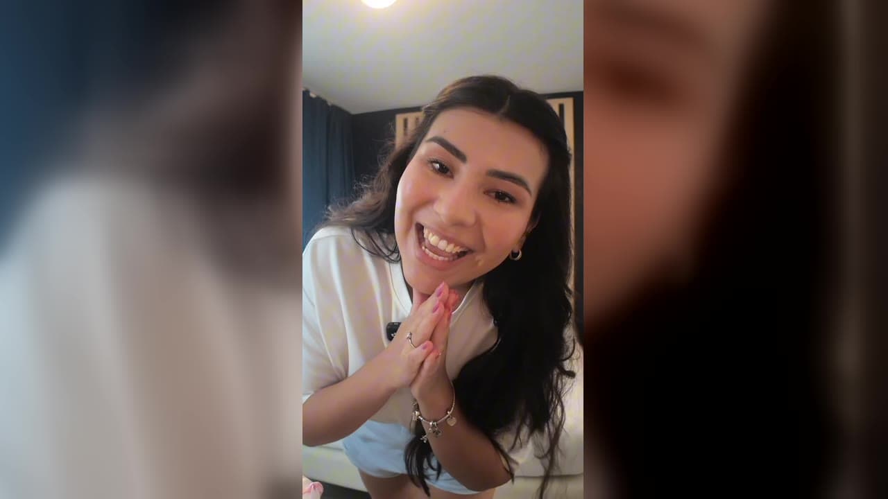 Karol Barbosa sorrindo com as mãos juntas no quarto de hotel, animada para ir à Disney