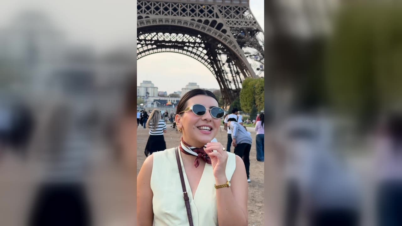 Karol Barbosa sorrindo em frente à Torre Eiffel, em Paris