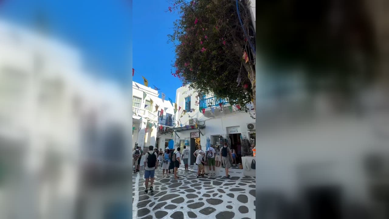 Ruas brancas de Chora, em Mykonos, com bandeirinhas coloridas e lojas